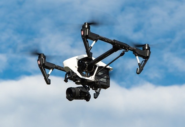 Image showing a drone in flight with a high resolution camera connection attached.